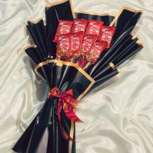 Black wrapper luxury bouquet with 8 KitKat chocolates and 4 red roses, tied with a red ribbon, elegant gift arrangement.